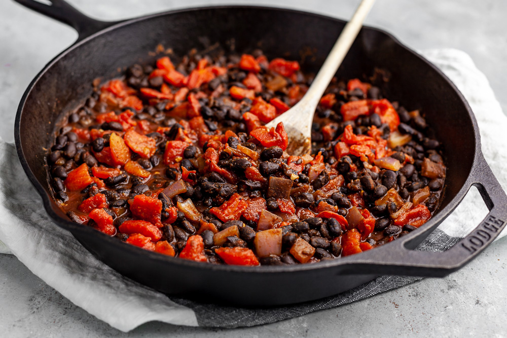 cooking beans and tomatoes in cast iron skillet plant based recipe