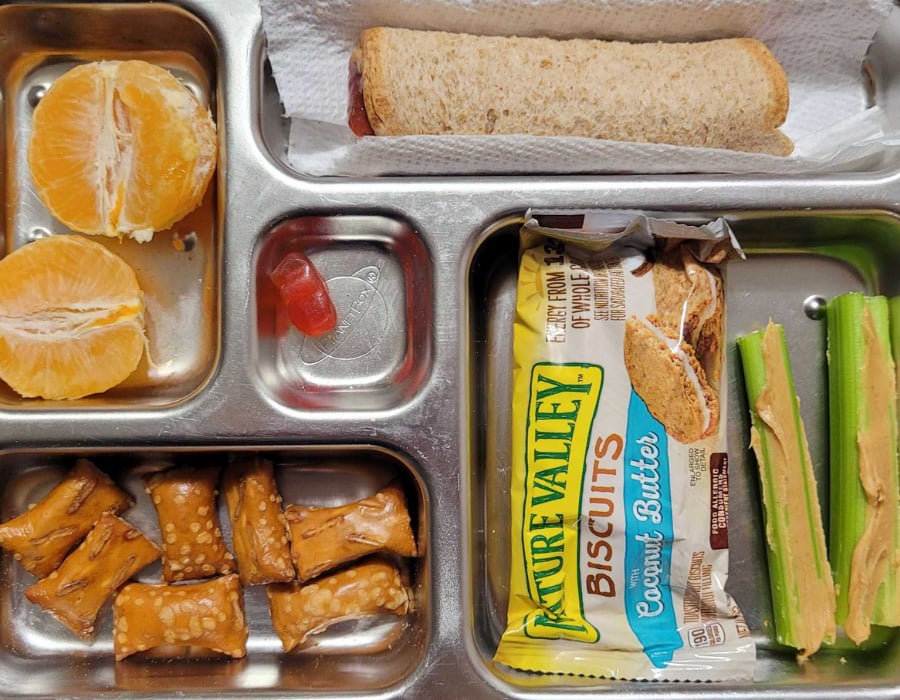 easy plant based lunch idea for kids Main: Peanut butter and jelly rollup
Vegetable: Celery with peanut butter
Fruit: Mandarin orange
Side: Pretzel nuggets and packaged snack
Treat: Gummy vitamin 