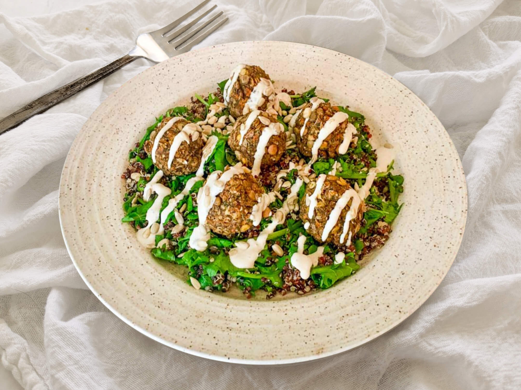 Lentil mushroom meatballs over quinoa and baby kale sauté with dijon thyme dressing.